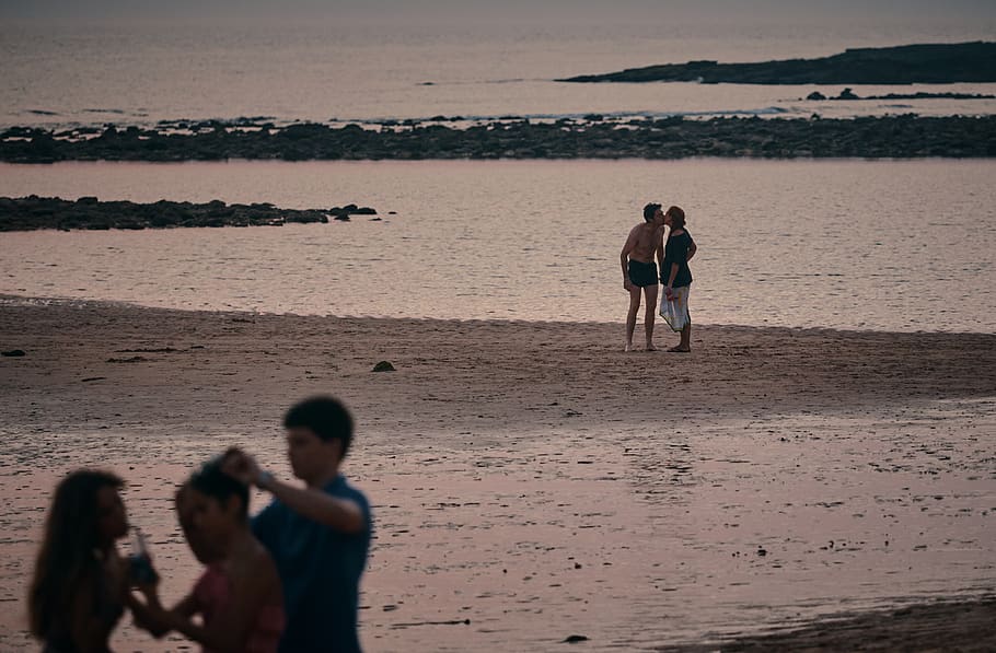 couple kissing on beach during daytime, person, human, shorts
