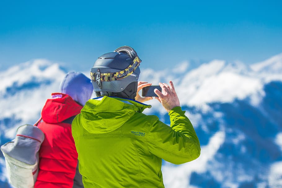 Man in Green Jacket and Gray Helmet Holding Phone Standing Next to Person in Red and Black Jacket HD wallpaper