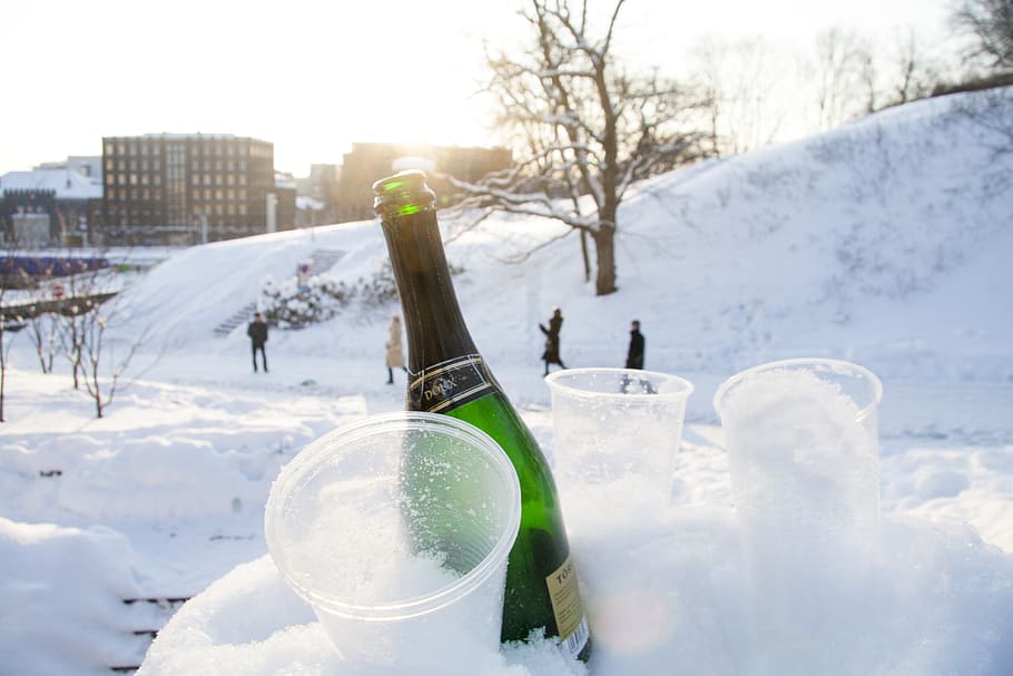 wine bottle beside disposable cups on snow, person, human, drink