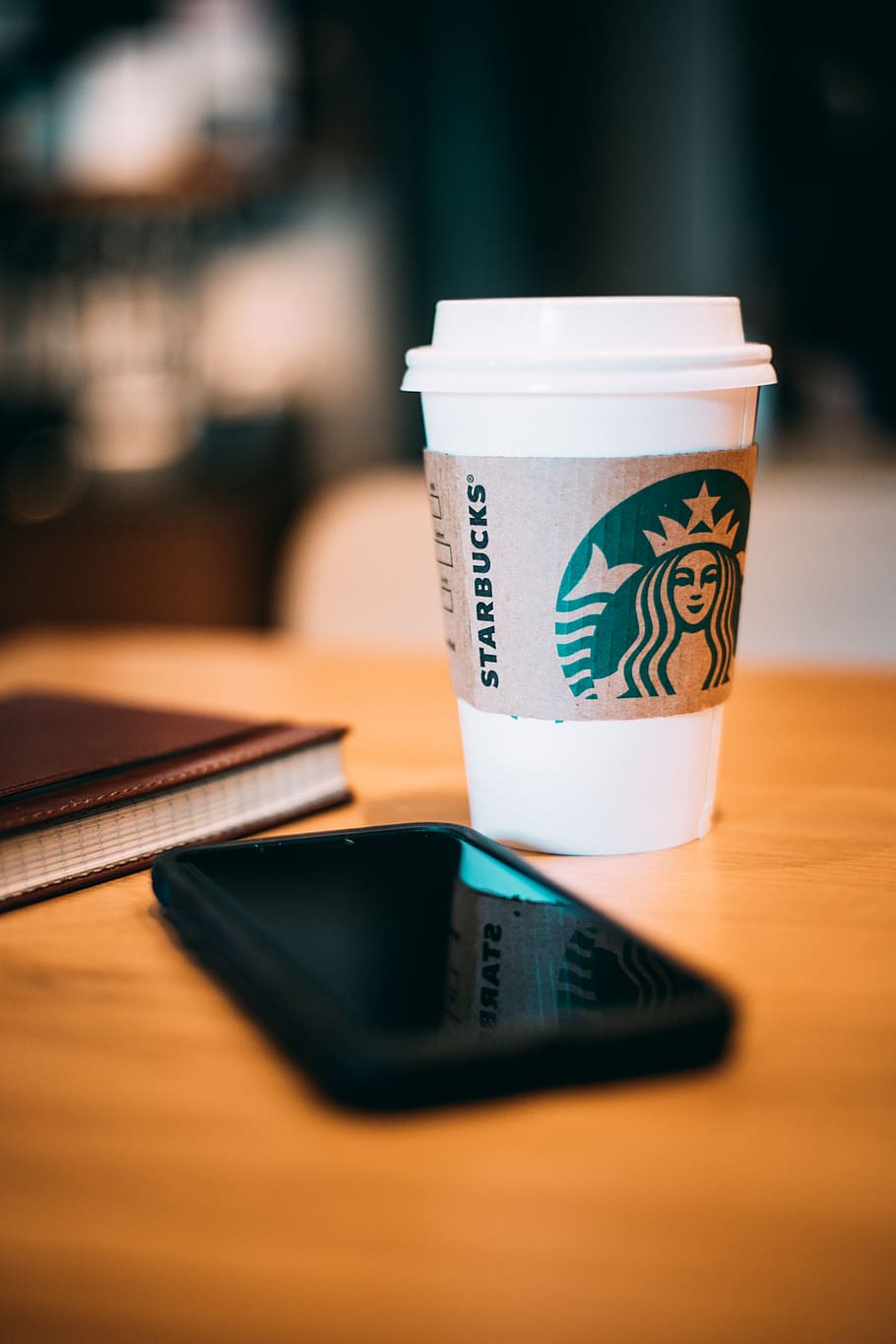 black smartphone beside a white Starbucks cup, drink, table, food and drink