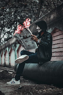 Man Wearing Mask Sitting Down and Holding Newspaper With Fire HD wallpaper