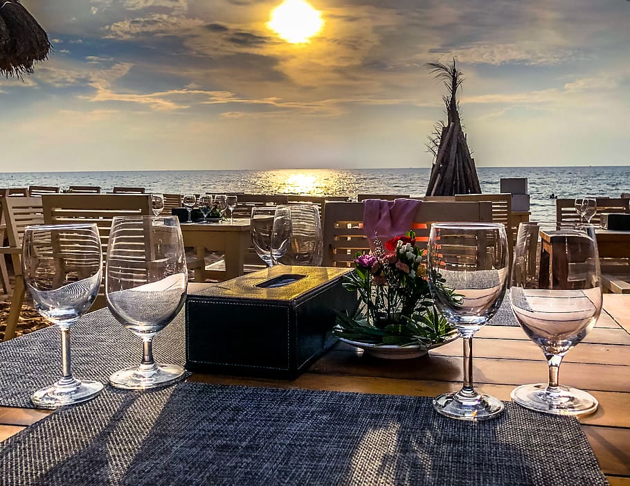 six long-stem wine glasses on brown table beside sea during daytime