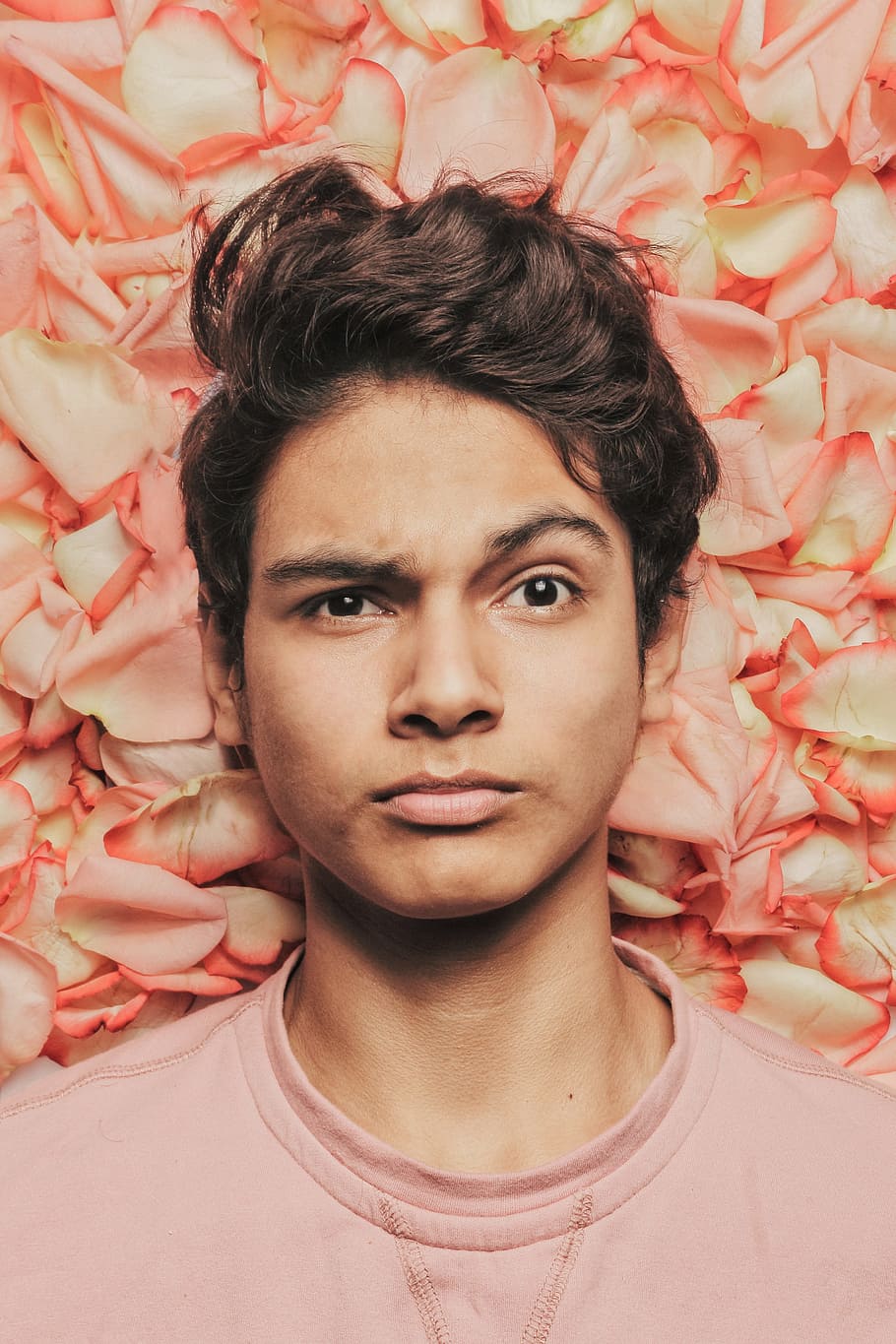 man standing against petaled flowers, face, portrait, face expression HD wallpaper
