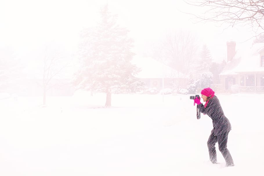Woman in Pink Hijab Holding Black Dslr Camera Under Raging Snow during Daytime