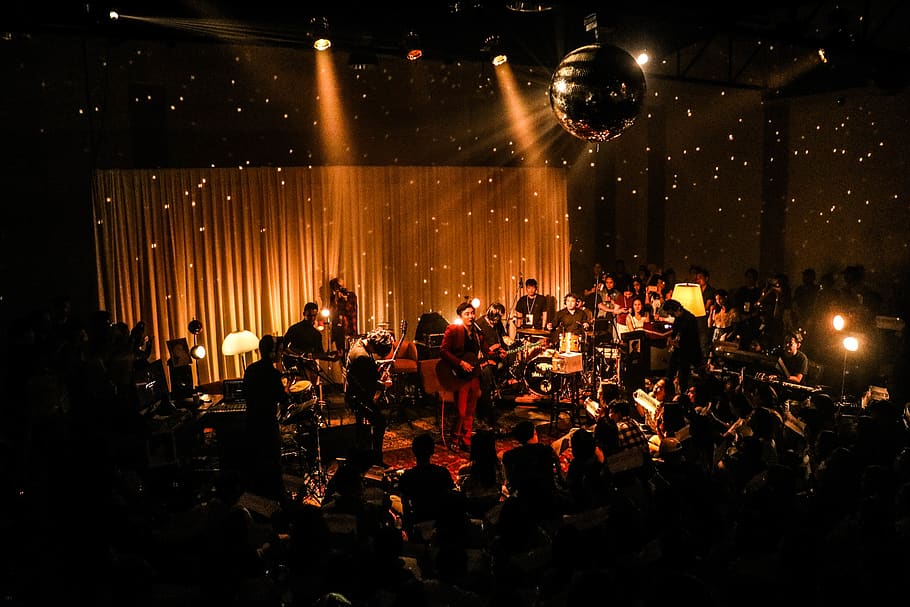 band inside room with disco ball, stage, crowd, musical instrument
