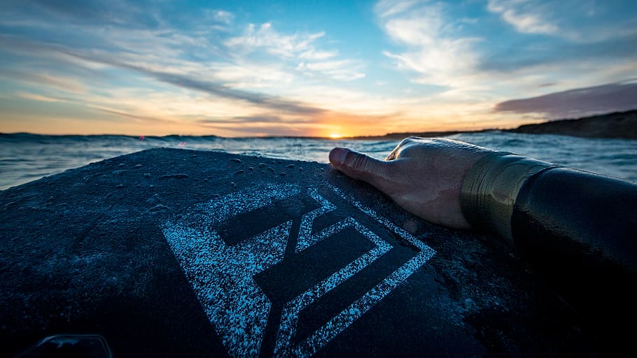 Person Holding Black and Gray Board Facing Blue Sea Under Blue Sky HD wallpaper