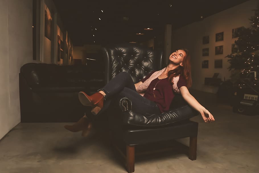 Woman in Maroon Scoop-neck Shirt Sitting on Black Leather Sofa Chair