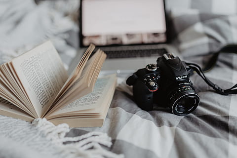 A camera, MacBook, and a book waiting in bed, room, computer HD wallpaper
