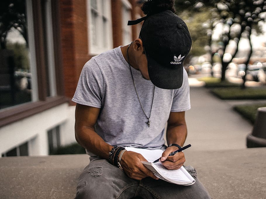 people, man, guy, black, cap, hat, notebook, pen, write, sitting HD wallpaper