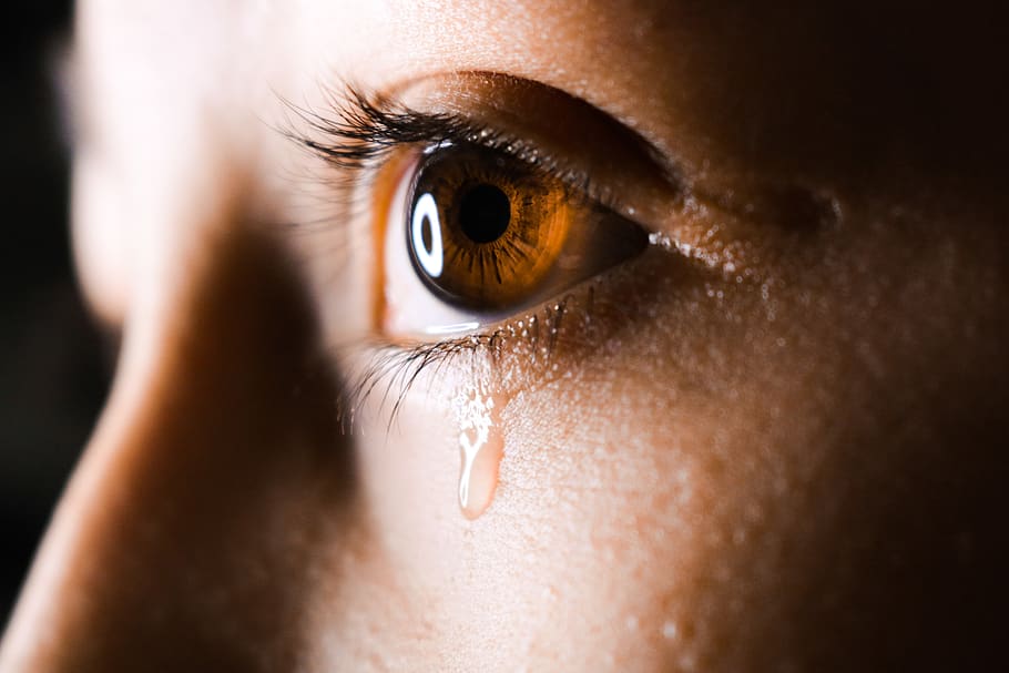 close-up photo of human eye with tear drops, contact lens, person