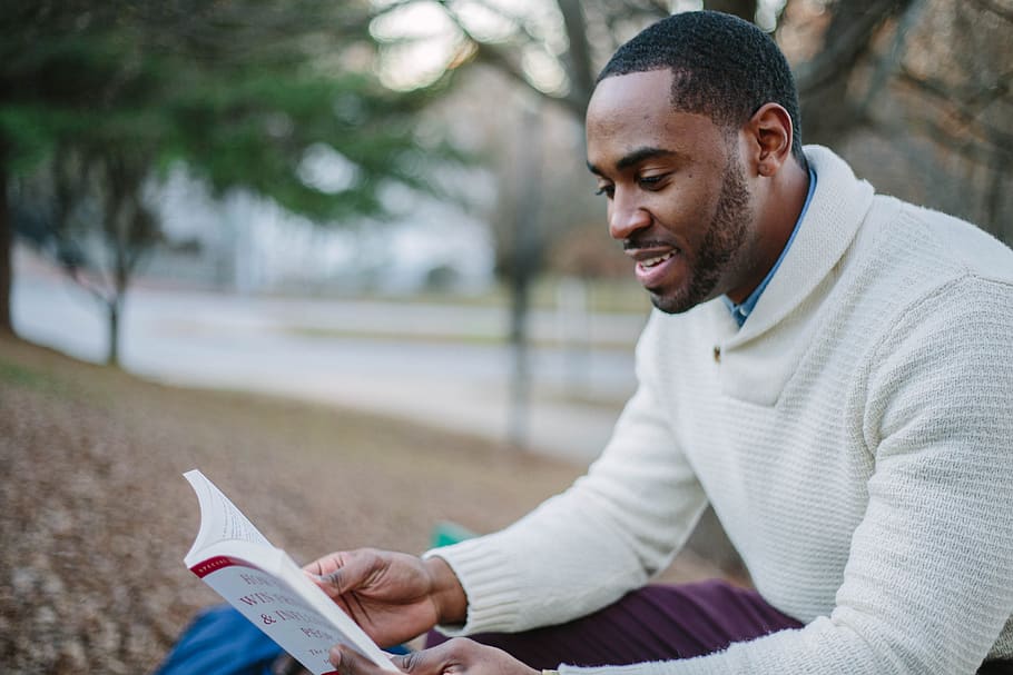 man wearing white sweater while reading book, one person, young adult HD wallpaper