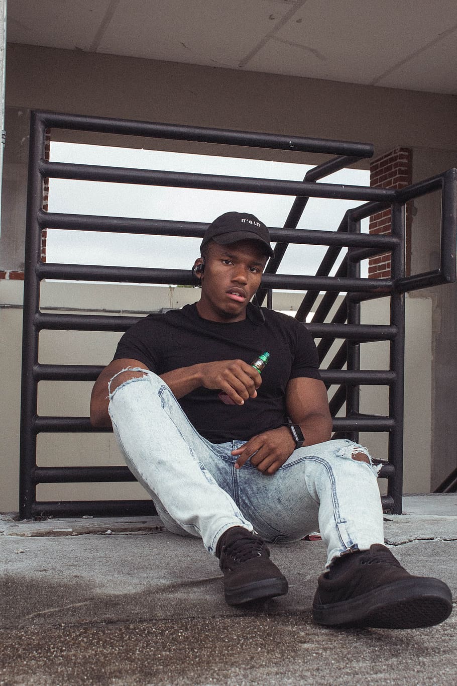 Man Sitting Near Black Railings, cap, indoors, person, vape, wear HD wallpaper