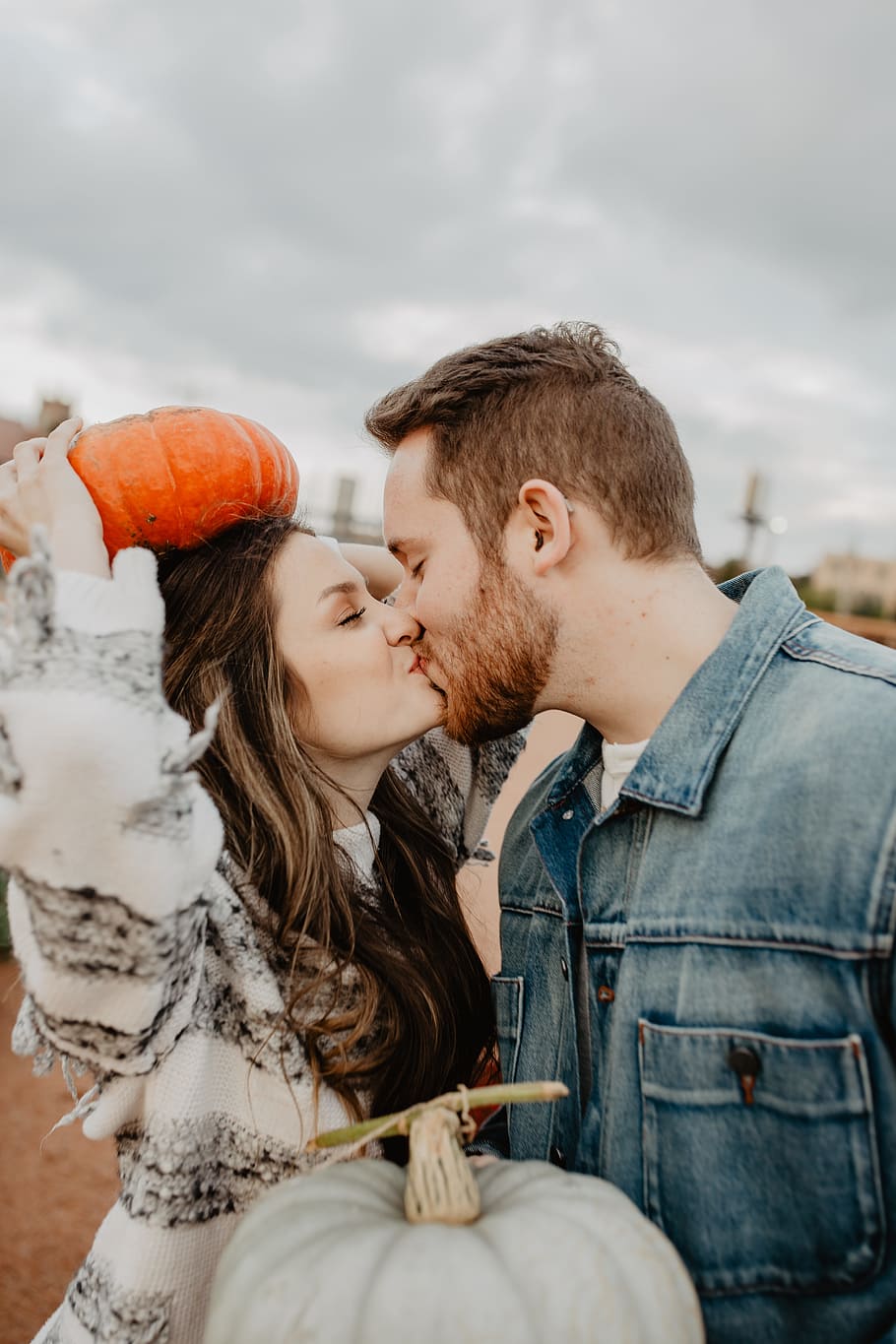 man and woman kissing holding squash during daytime, fall, pumpkin