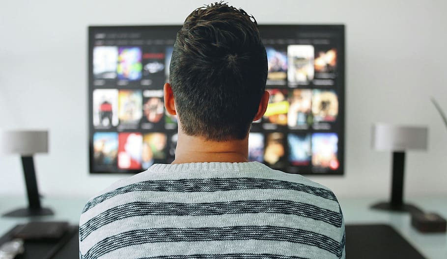 Man sitting in front of large television, browsing options., tv