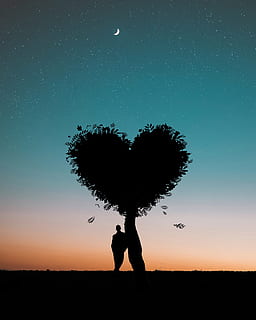 Silhouette Photo of Man Leaning on Heart Leaf Shape Tree during Dawn HD wallpaper