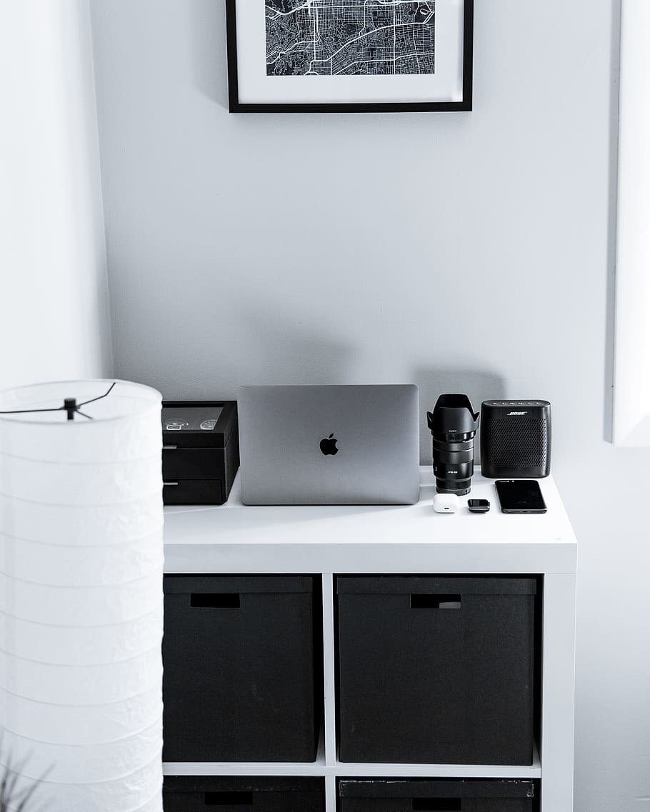 silver MacBook beside black camera lens and speaker on dresser HD wallpaper