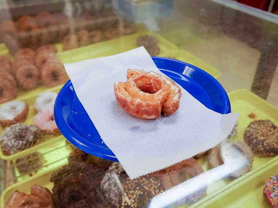 Glazed cake donut sitting on a blue plate inside of a donut shop., HD wallpaper