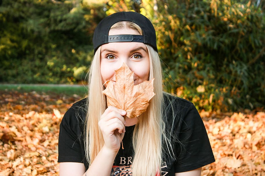 Photo of Woman Holding Dry Leaf, adorable, beautiful, blur, cap HD wallpaper
