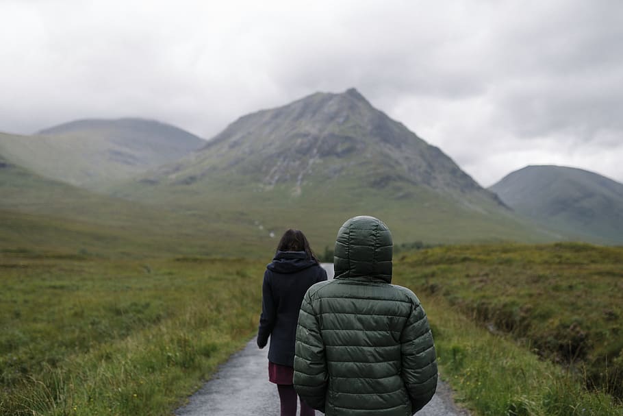 Two People Wearing Bubble Jackets While Walking on Pathway Between Green Grass HD wallpaper