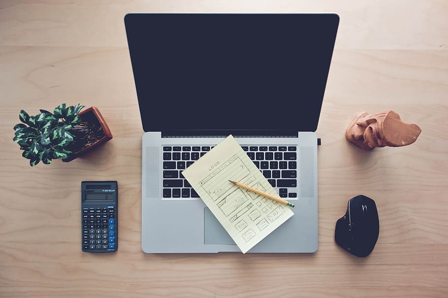 High Angle View of Home Office Desk Setup, with a MackBook, Calculator Indoor Desk Plant and a Wireless Mouse with Wooden Mini Statue. HD wallpaper