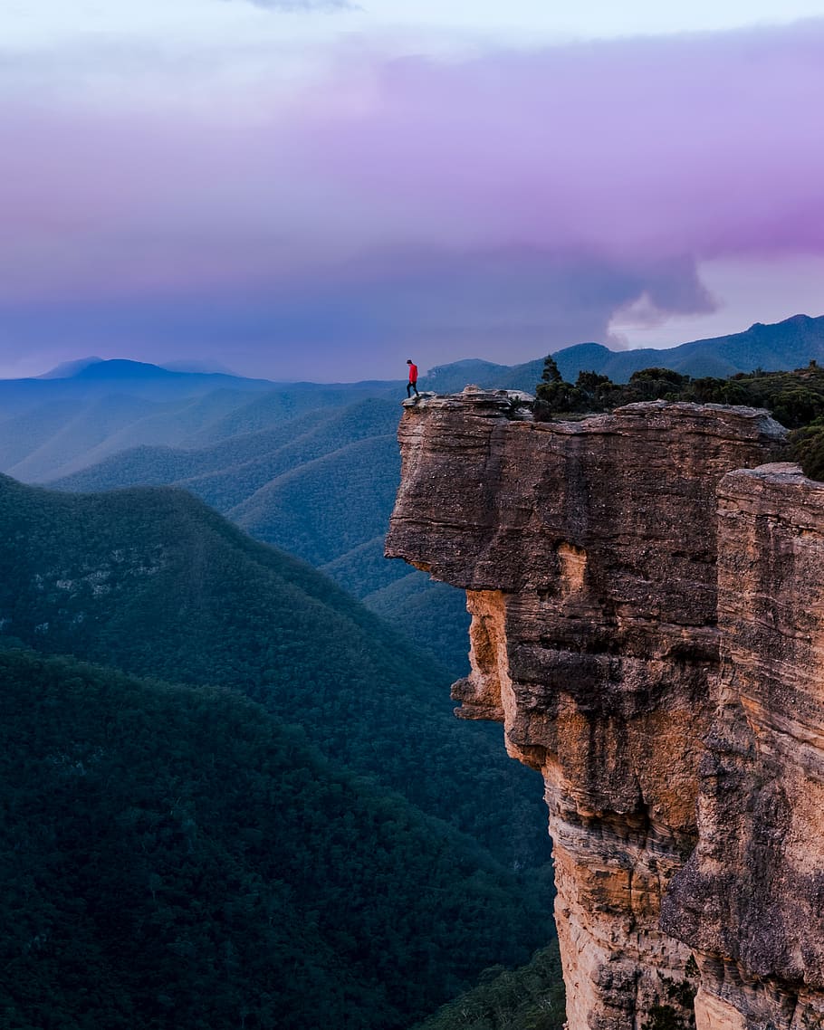 person standing on the edge of a cliff during daytime, nature