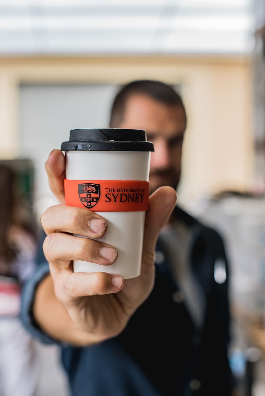 man holding sydney drinking cup, front view, focus on foreground HD wallpaper