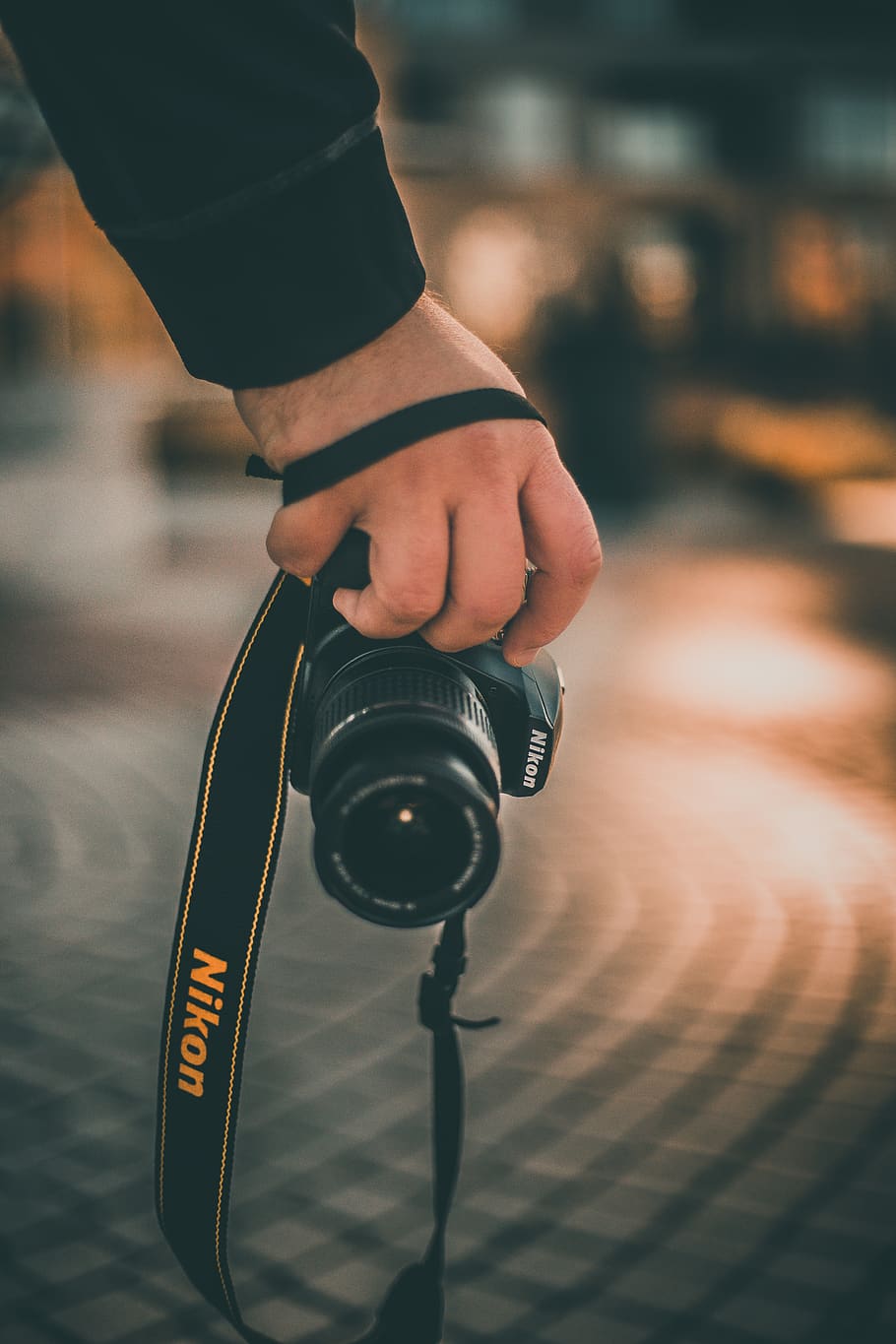 person holding black Nikon DSLR camera, human, electronics, strap