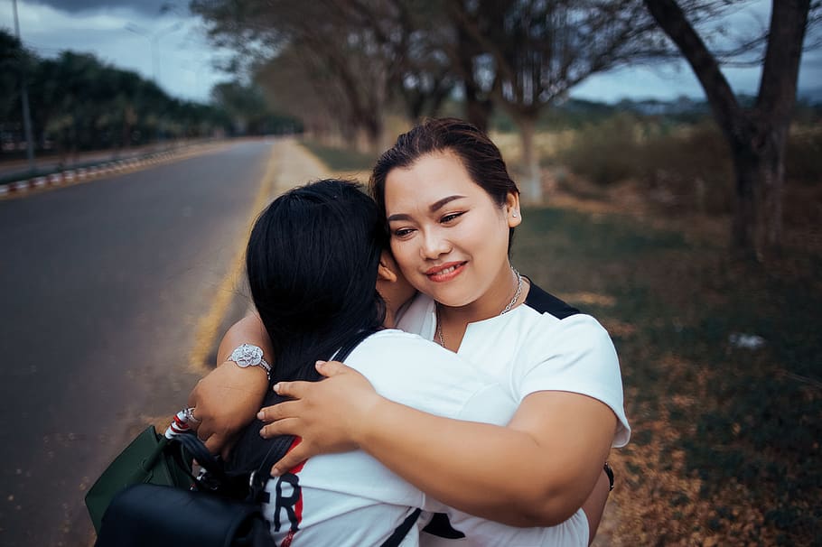 Two Women Hugging Each Other Standing on Pathway of the Road HD wallpaper