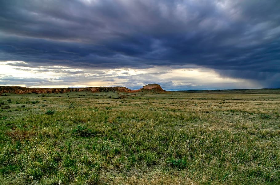 Dark roiling clouds above a sweeping grass floor envelope rock formations creating an enchanted dreamlike visage. This is Pawnee National Grasslands, Colorado, during early spring. These grasslands are located on the Colorado prairie near the Wyoming state line., HD wallpaper