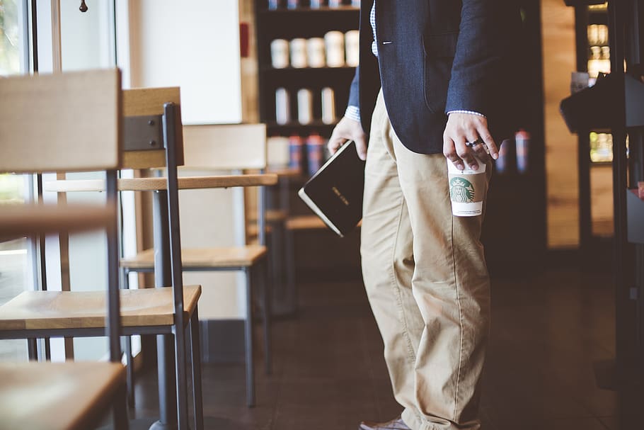 man holding a book and plastic cup, midsection, one person, indoors HD wallpaper