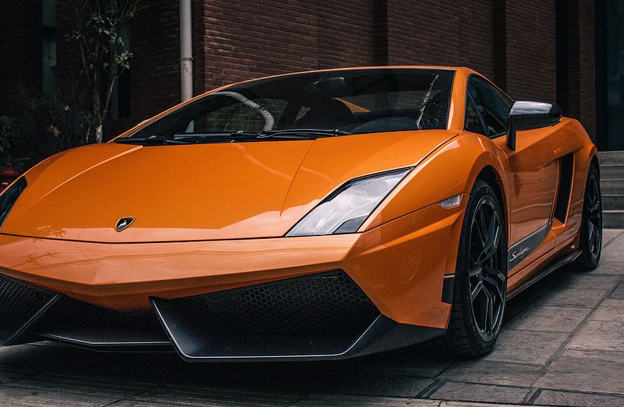 Side view of orange lamborghini with projector headlights and alloy wheels