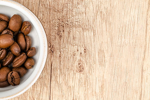 Coffee Beans on White Ceramic Bowl on Top of Brown Wooden Surface HD wallpaper