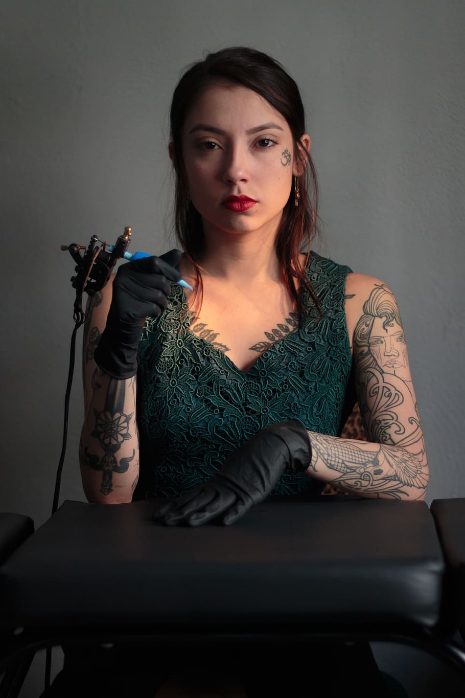 woman sitting and holding tattoo machine, front view, one person