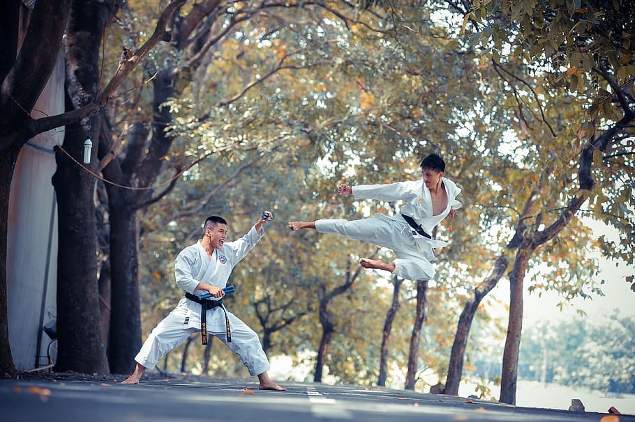 two men performing karate near trees during daytime, full length
