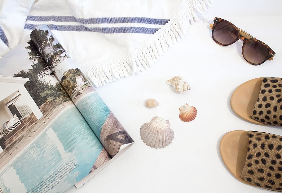 opened magazine beside seashells, slide sandals, sunglasses and towel on white surface, HD wallpaper