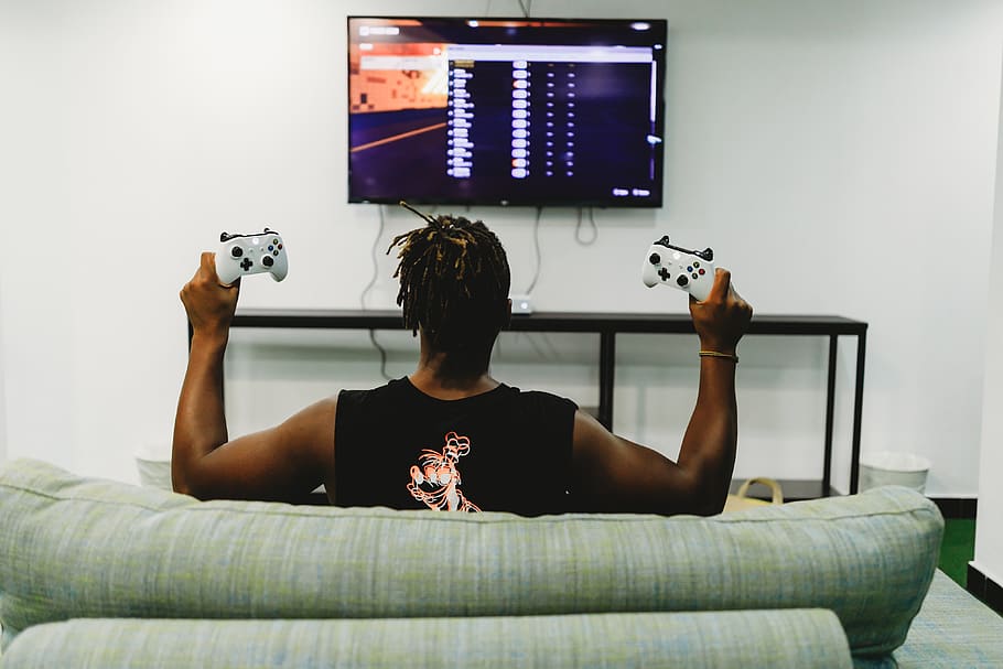 man sitting on couch holding controllers, one person, technology HD wallpaper