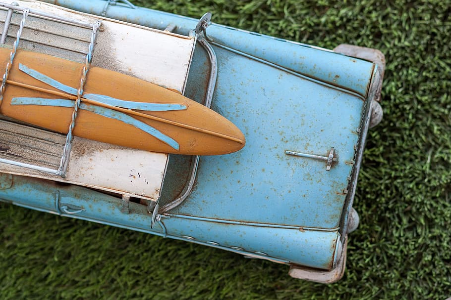 brown surfboard on rusted blue vintage car, toy, old, grass, play