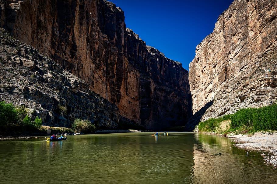 Body of Water Between Rocky Mountain Under Clear Blue Sky during Daytime HD wallpaper