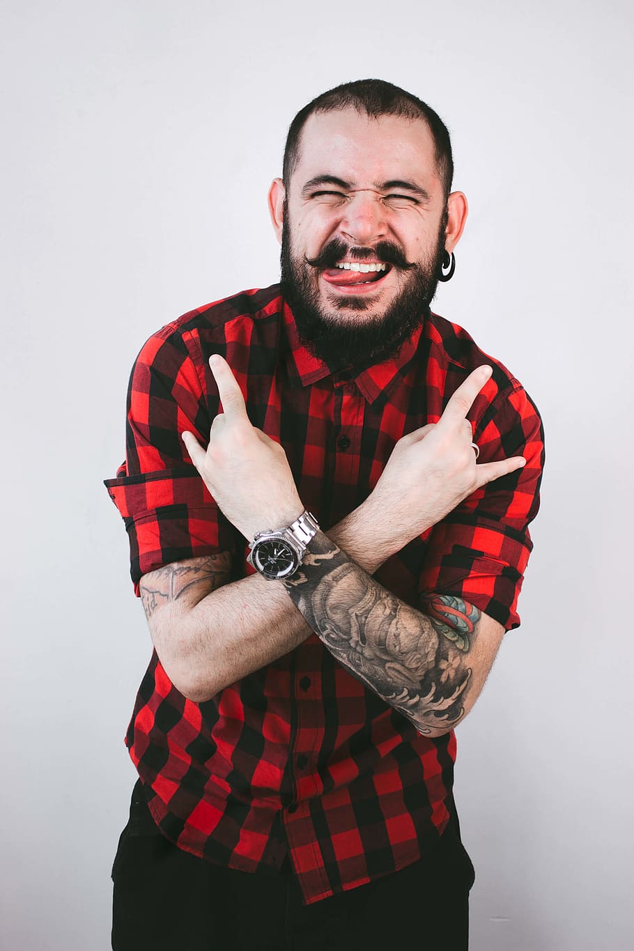 man wearing red and black checked button-up shirt doing rock hand sign