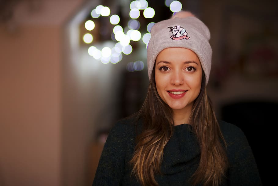 woman standing inside room, apparel, clothing, cap, hat, beanie