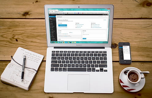 Turned-on Macbook Air Beside Black Iphone 4, Cup of Tea, and Notebook on Brown Wooden Surface HD wallpaper