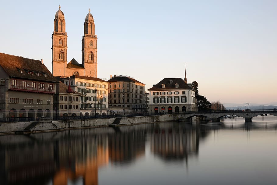 Cathedral Behind Building Beside Body of Water With Stone Bridge HD wallpaper