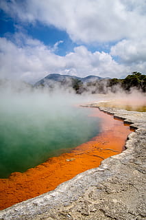Brown Surface Beside Body of Water in a Distant of Mountains Under White Clouds during Daytime HD wallpaper