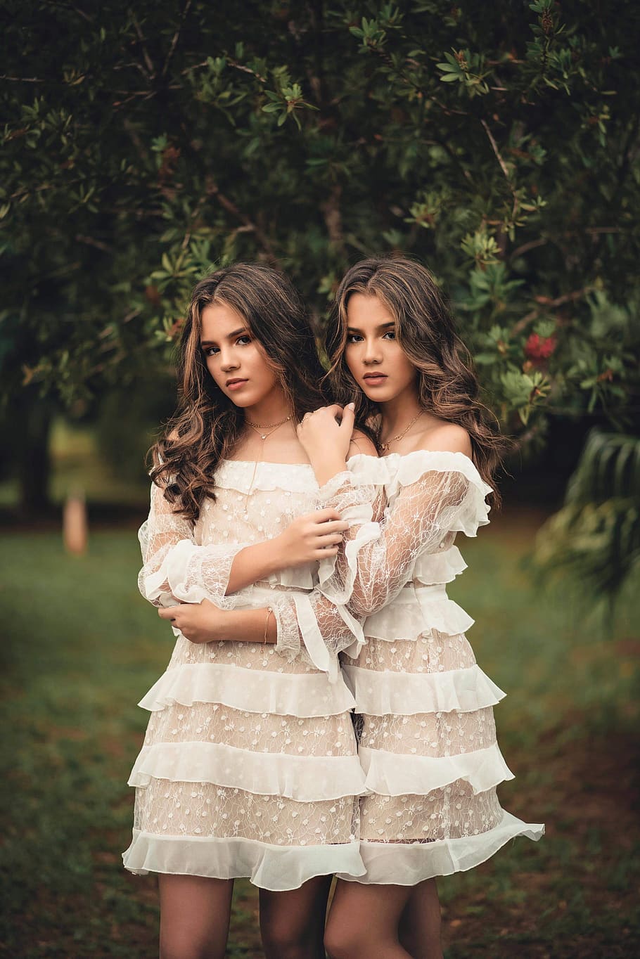 Two Standing Women Wearing White Off-shoulder Dresses Near Green Trees