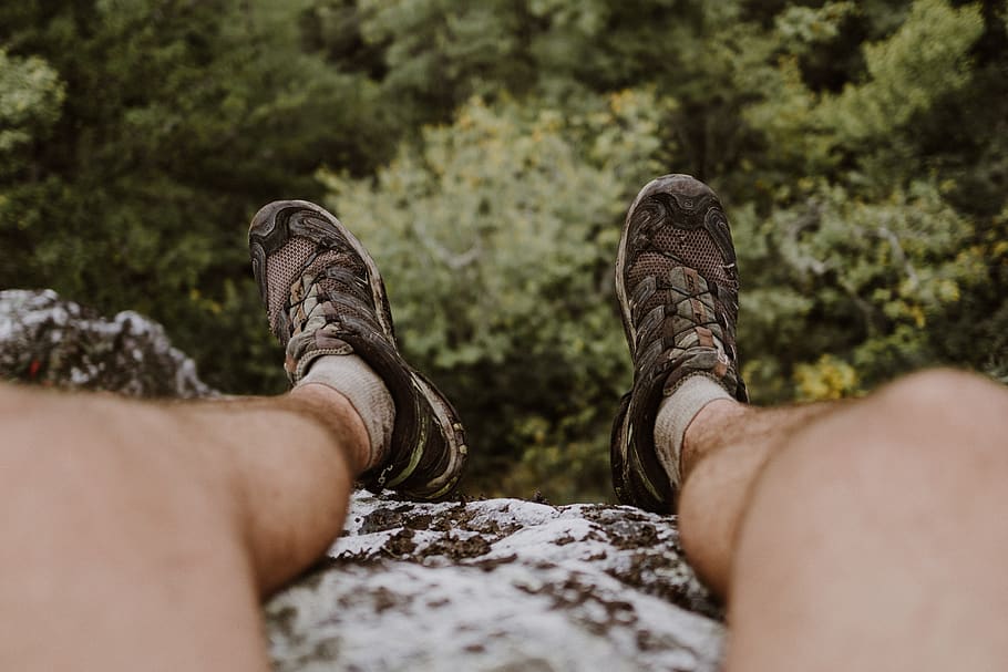 person wears trek shoes sits on cliff, apparel, clothing, human