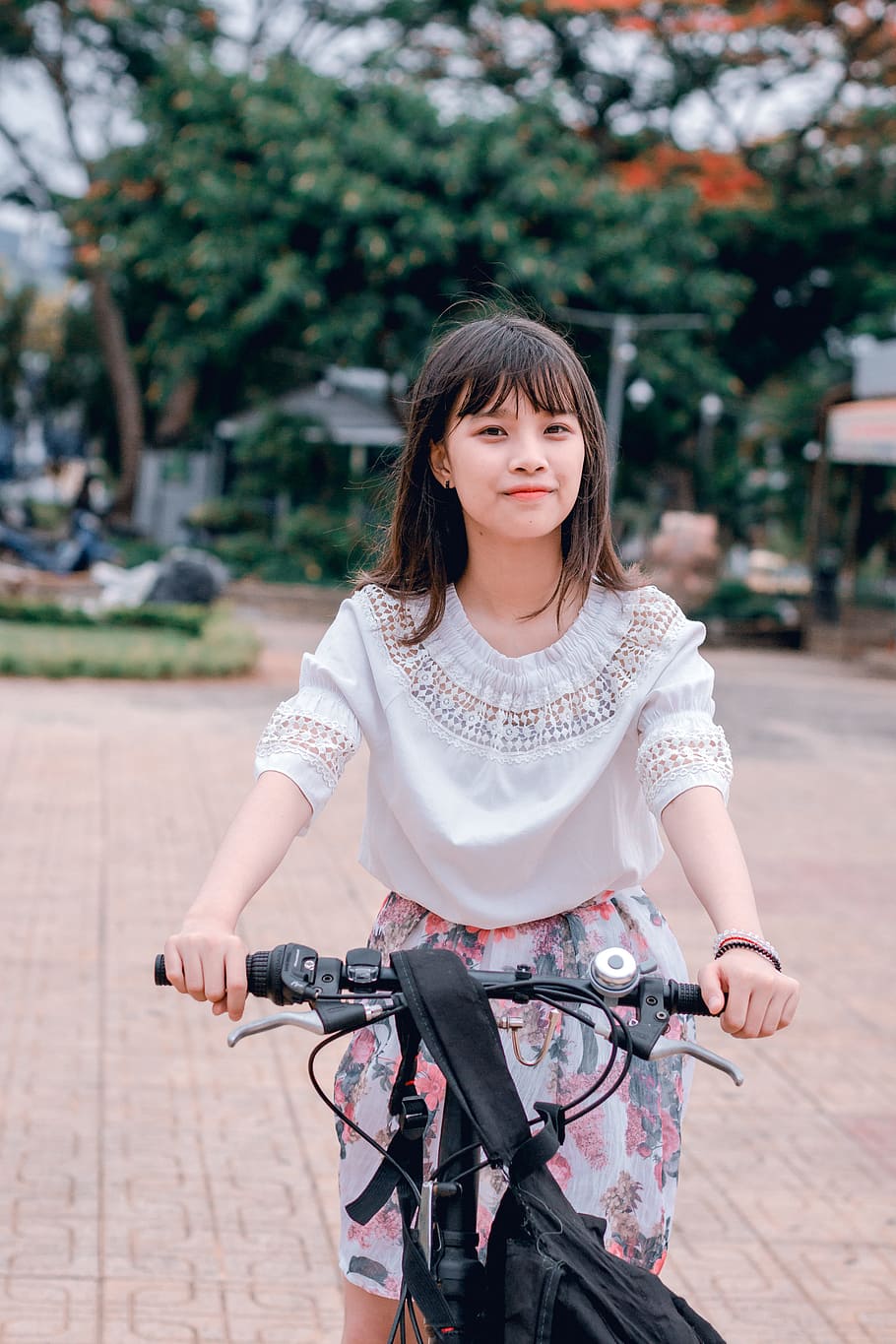 Woman Wearing White Blouse and Multicolored Floral Skirt Riding Bike HD wallpaper