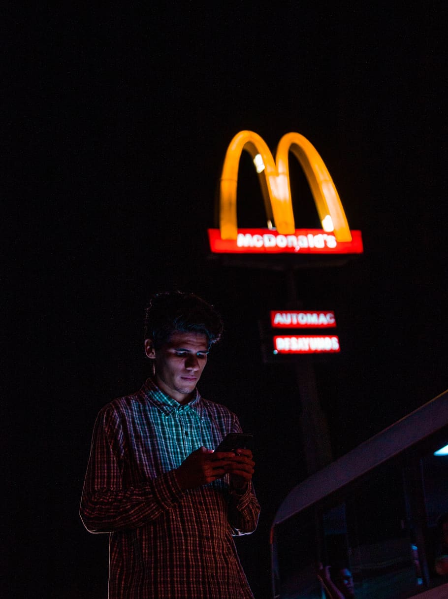 man using Android smartphone near McDonalds, night, illuminated HD wallpaper