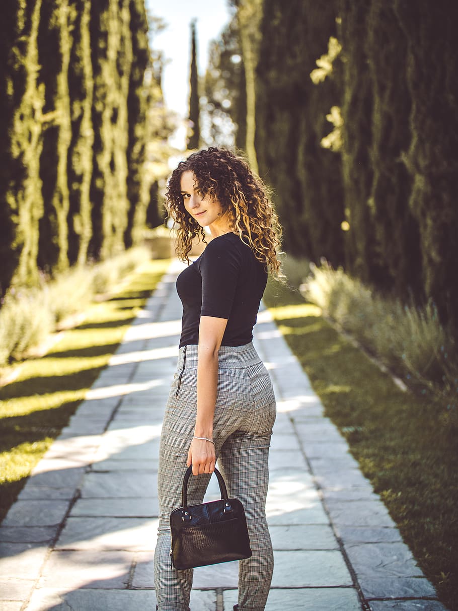 woman standing on pathway between pine trees, real people, one person HD wallpaper
