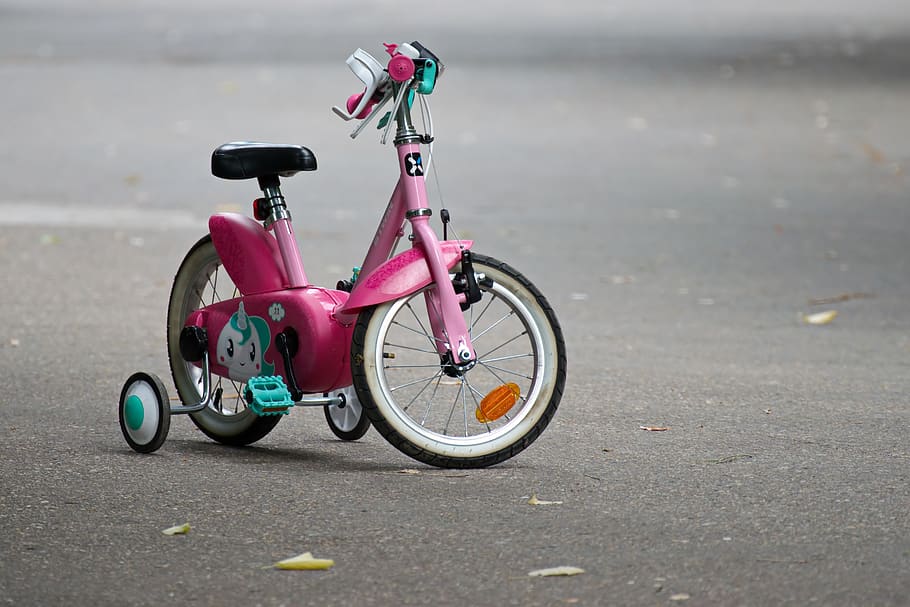 Pink Bike With Training Wheels on Gray Pave Road, action, asphalt