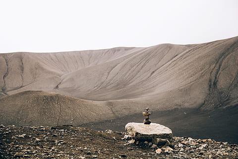 Stacked stones rock art in the desert hills landscape with black sand HD wallpaper